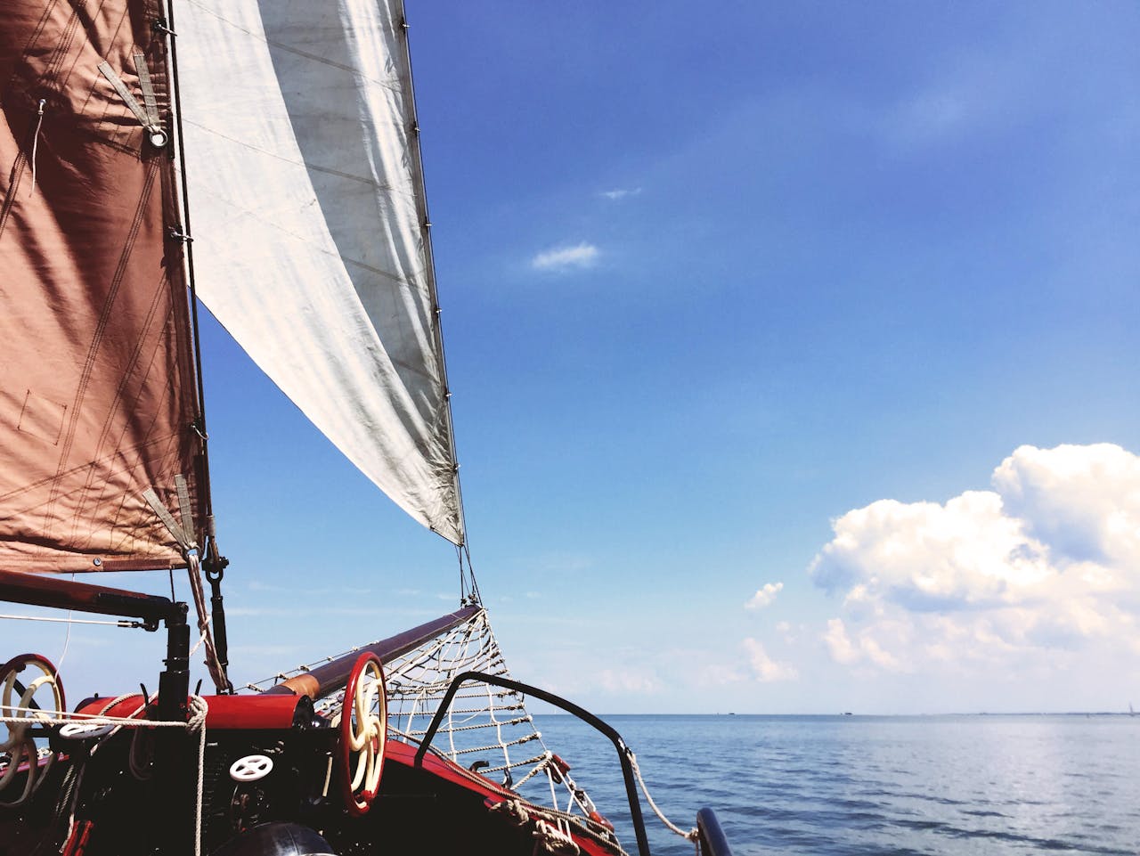 A sailboat navigating the calm ocean under a clear blue sky, perfect for leisure sailing.