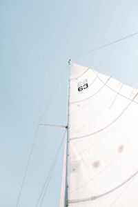 Minimalist view of a sailboat's mast and sails under a clear blue sky, creating a sense of adventure and freedom.